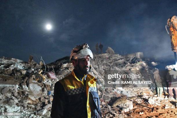 Graphic content / TOPSHOT - A member of the Syrian civil defence, known as the White Helmets, stand near the rubble of a collapsed building late on...