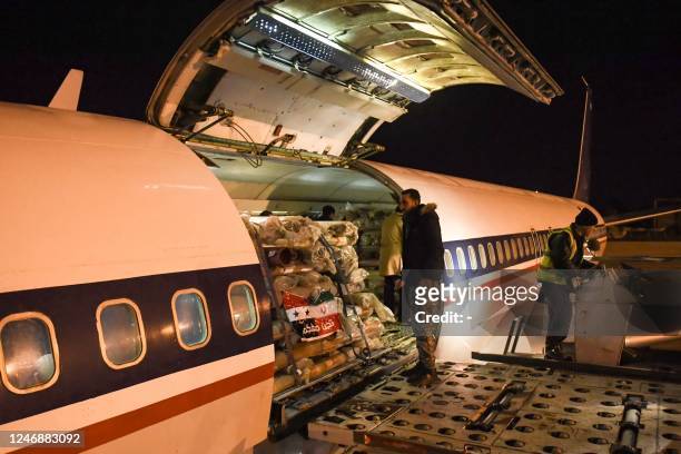 Workers unload aid sent by Iran by plane, at the airport in Syria's northern city of Aleppo early on February 8 following a deadly earthquake. - The...