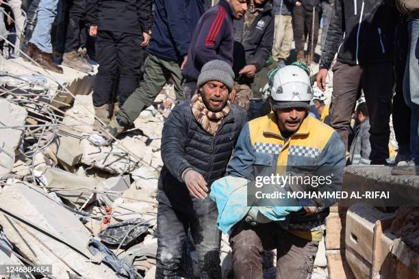 Man reacts as the body of his baby pulled out from the rubble, is taken away by a Syrian White Helmet rescue worker, in the town of Harim in Syria's...