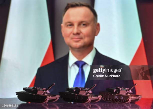 Illustration of a mini replica of Leopard tanks, seen in front of a photo of Andrzej Duda, President of the Republic of Poland, displayed on a...