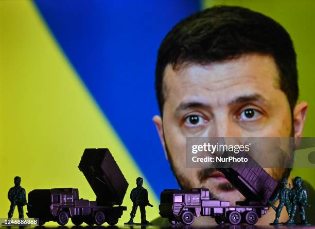 Illustration of a mini replica of MIM-104 Patriot, a surface-to-air missile system and figures of soldiers, seen in front of a photo of Volodymyr...