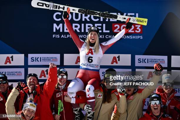 Third-placed Austria's Cornelia Huetter celebrates with team staff on the podium after the Women's Super-G event of the FIS Alpine Ski World...