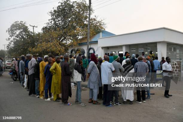 People queue early in the day to withdraw money from cash dispensers that is crippled by cash shortages at a bank in Kano, northwest Nigeria, on...