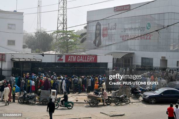 Dozens of people anxiously wait to withdraw money from cash dispensers that is crippled by cash shortages at a bank in Kano, northwest Nigeria, on...