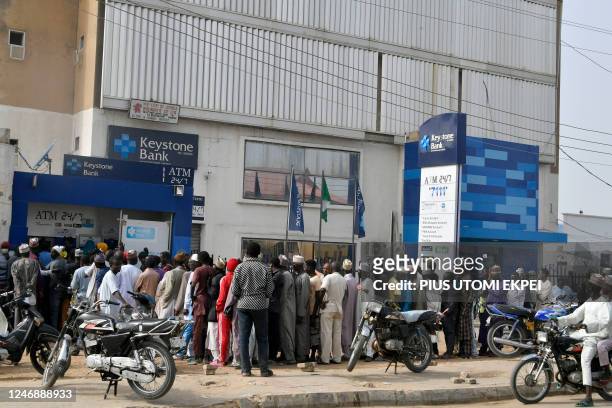 People queue early in the day to withdraw money from cash dispensers that is crippled by cash shortages at a bank in Kano, northwest Nigeria, on...