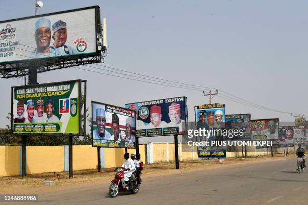 Motorcycle taxi rides past campaign billboards of candidates of political parties vying for elective offices in Kano, northwest Nigeria, on February...