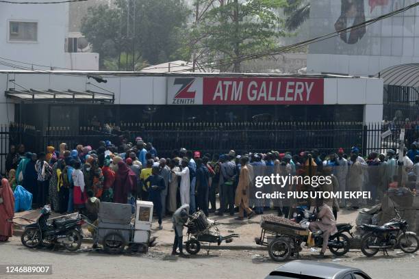 Dozens of people anxiously wait to withdraw money from cash dispensers that is crippled by cash shortages at a bank in Kano, northwest Nigeria, on...