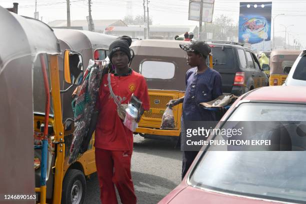 Vendors sell wares in a traffic gridlock in Kano, northwest Nigeria, on February 8, 2023. - Africa's most populous country has been crippled by fuel...