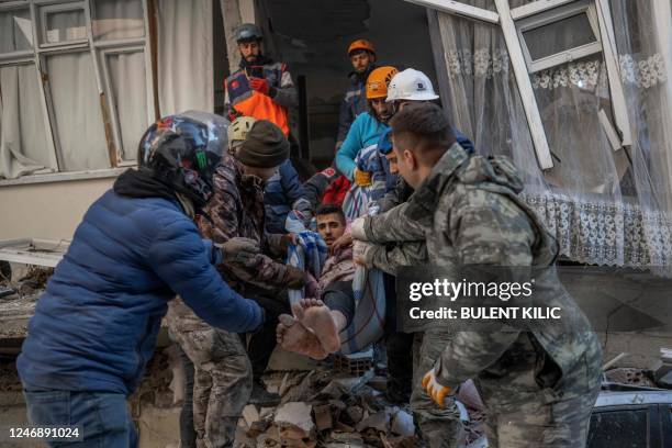 Rescuers carry a man as he is rescued after being stuck in rubble for two days in Hatay, southeastern Turkey, on February 8 two days after a strong...