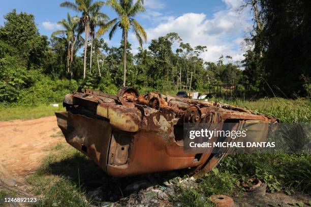 Burnt and rusted car is seen at Porto do Arame, located on the banks of the Uraricoera river, the main access point for people trying to leave...