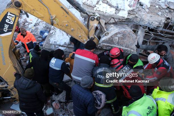 Local people and rescue volunteers carry a body covered with a blanket during rescue operations on February 8, 2023 in Elbistan Turkey. A...