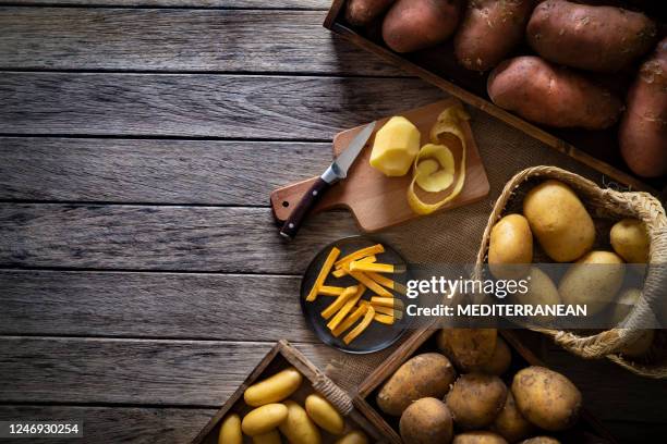 french fries potatoes on a rustic wooden board table with raw potatoes around - batata imagens e fotografias de stock