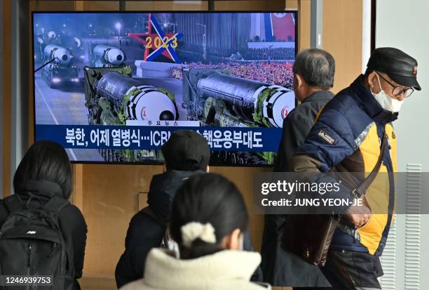 People watch a television screen showing a news broadcast with an image of a North Korean military parade held in Pyongyang to mark the 75th founding...