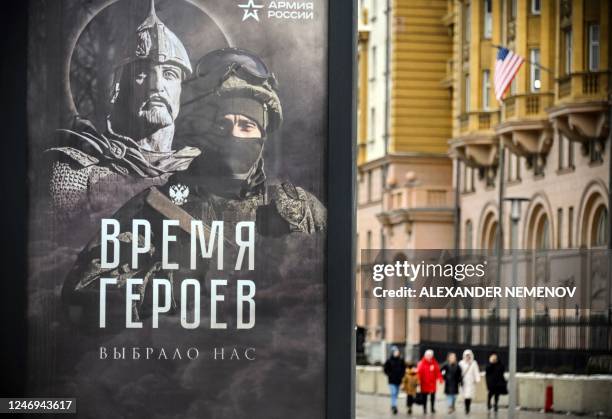 The US Embassy building is seen behind a social advertisement billboard showing a Russian soldier in front of his ancient predecessor and reading...