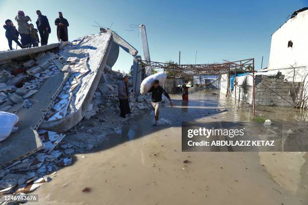 Syrian man carries a sac past a destroyed building in a flooded area after the collapse of a dam on the Orontes river near al-Tulul village in...