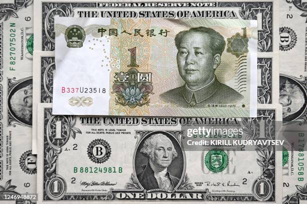 This photograph taken on February 9, 2023 shows a Chinese yuan banknote and US dollar banknotes in Moscow.