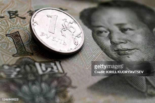 This photograph taken on February 9, 2023 shows a Russian ruble coin and a Chinese yuan banknote in Moscow.