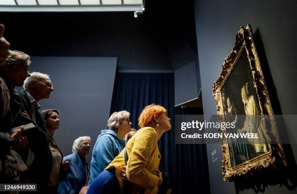 Visitors look at the painting "Mistress and Maid" during the opening of the Johannes Vermeer exhibition in the Rijksmuseum in Amsterdam on February...