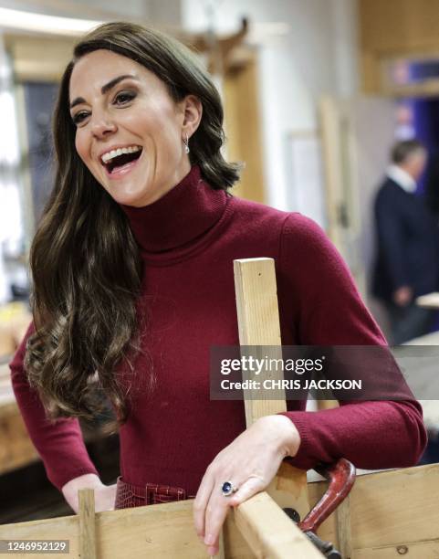 Britain's Catherine, Princess of Wales laughs as she helps to refurbish a boat during a tour of the National Maritime Museum Cornwall on February 9,...