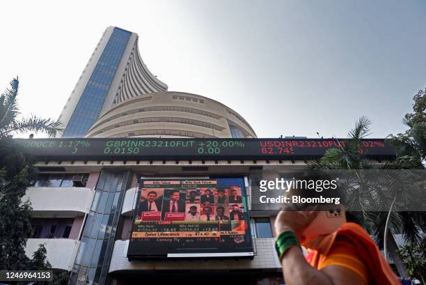 Pedestrian passes a news broadcast on the Adani Group outside the Bombay Stock Exchange building in Mumbai, India, on Thursday, Feb. 9, 2023. Adani...