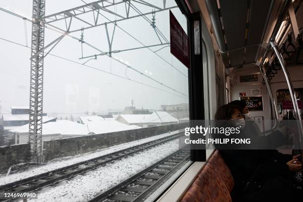Passengers travel on the train as it snows in Tokyo on February 10, 2023.