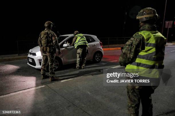 Chilean military personnel check vehicles at a security checkpoint during a curfew in the forest fire zone in Tome, the southern region of Chile,...