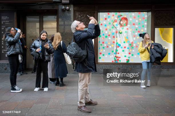 Members of the public interact with a screen featuring the artist Yayoi Kusama in a window of Harrods in Knightsbridge, on 9th February 2023, in...