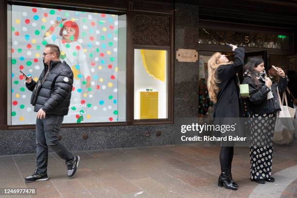 Members of the public interact with a screen featuring the artist Yayoi Kusama in a window of Harrods in Knightsbridge, on 9th February 2023, in...