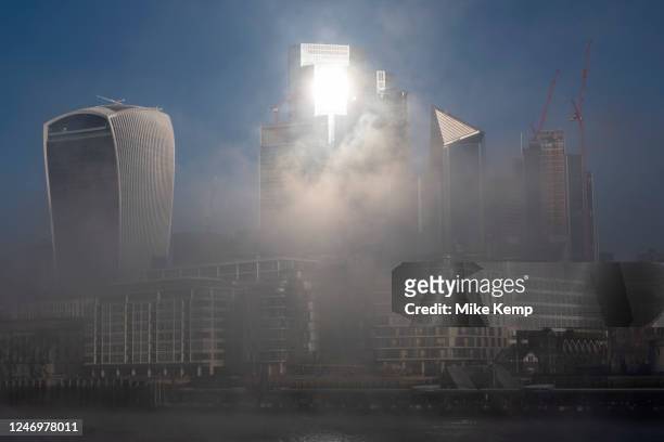 Thick fog overlooking the City of London skyline making a peaceful yet eerie atmosphere as structures appear and disappear over the River Thames and...
