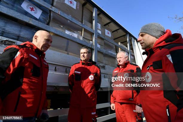 Members of the Croatian Red Cross chat in front of trucks, containing humanitarian aid, lining-up at the logistics center of the directorate of civil...