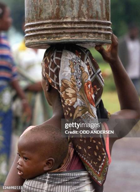 Young floodvictim sits on his mothers back as she is carrying water in a bucket at a displaced peoples camp in the central Mozambican town of...