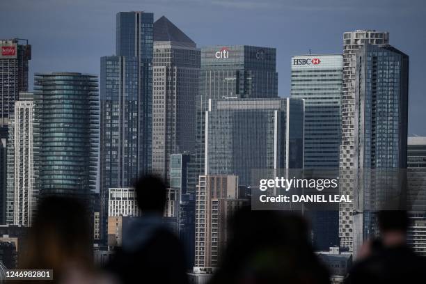 People look at Canary Wharf financial district, from Greenwich Park, south east London, on February 10, 2023. - Britain's economy has narrowly...