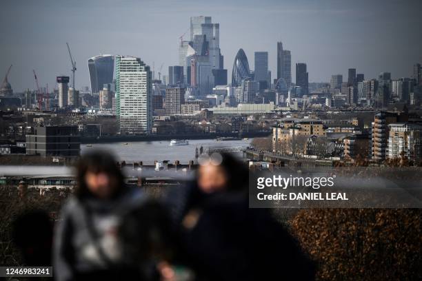 People walk in Greenwich Park, south east London, with the City financial district in the background, on February 10, 2023. - Britain's economy has...
