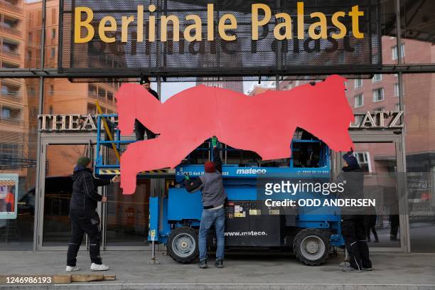 Workers hold a banner depicting the Berlinale bear, to be installed on the Berlinale Palast facade, six days ahead of the film festival opening, in...