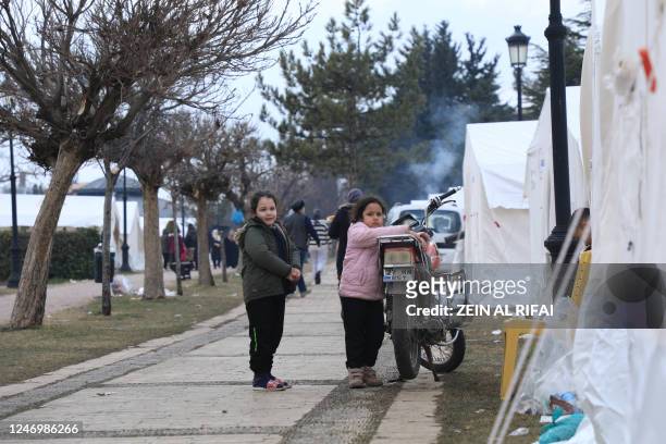 Displaced residents look on as they stand near a tent in a camp at Masal Park, in Gaziantep, on February 10 four days after a 7.8 magnitude...