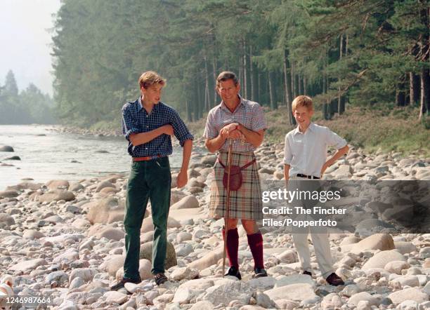 Prince William, his brother HRH Prince Harry and his father HRH Prince Charles wearing a kilt beside the River Dee on the Scottish Estate of Queen...