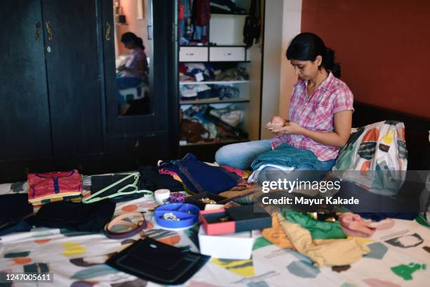 woman checks mobile while organising wardrobe - clean closet stock pictures, royalty-free photos & images