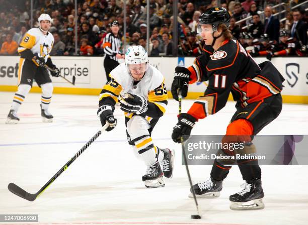 Trevor Zegras of the Anaheim Ducks skates with the puck with pressure from Jake Guentzel of the Pittsburgh Penguins during the second period at Honda...