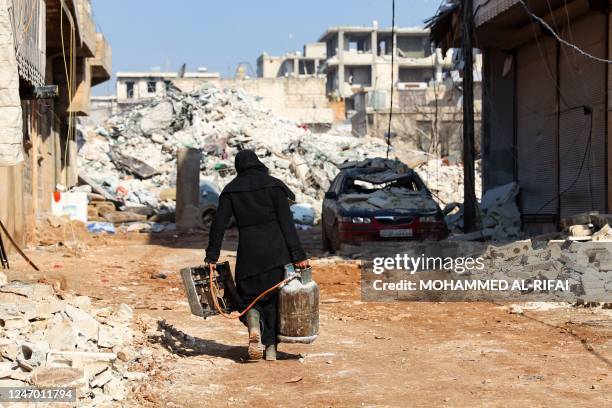 Woman salvages a small stove and a gas canister, as search and rescue operations continue days after a deadly earthquake hit Turkey and Syria, in the...