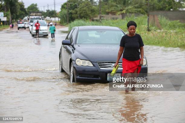 Woman walks through one of the flooded streets due to heavy rain in the Boane district of Maputo on February 11, 2023.