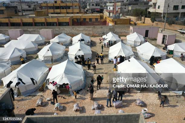 This aerial view shows Syrian White Helmet rescue workers distributing aid in a makeshift camp where tents set up by volunteers to temporarily...