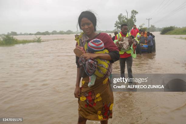 Woman walks with her baby after being evacuated from the floods caused by heavy rain in the Boane district of Maputo on February 11, 2023.