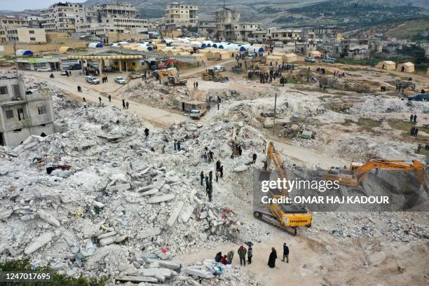 This aerial view shows rescuers searching for survivors amidst the rubble of collapsed buildings in the town of Harim in Syria's rebel-held...