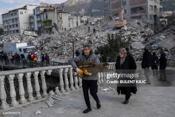 Man holds debris in front of destroyed buildings in the Antakia historical city in Hatay on February 11 after a 7.8-magnitude earthquake struck the...