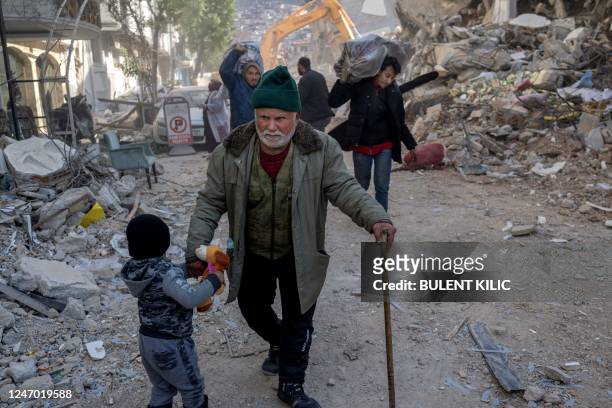 Syrian man and his grandson walk in the debris in the Antakia historical city in Hatay on February 11 after a 7.8-magnitude earthquake struck the...