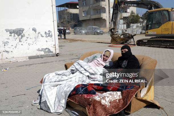 Men sit on a sofa under blankets on a street in Islahiya, in the hard hit region of Gaziantep, on February 11 five days after a 7.8 magnitude...