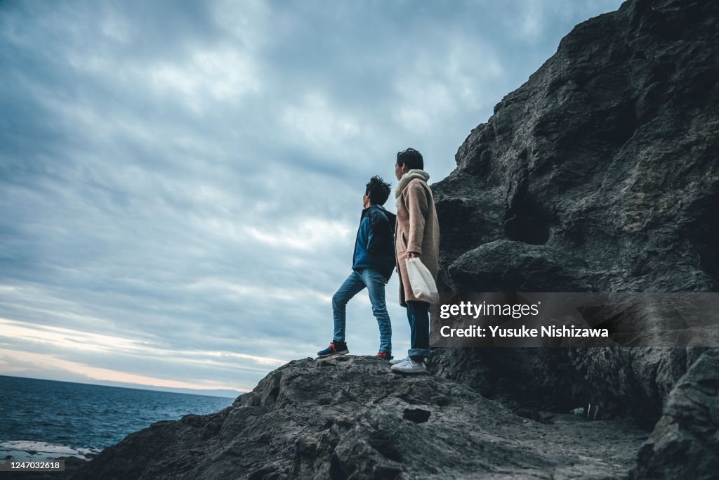 A boy and a girl on a rock, staring into the distance