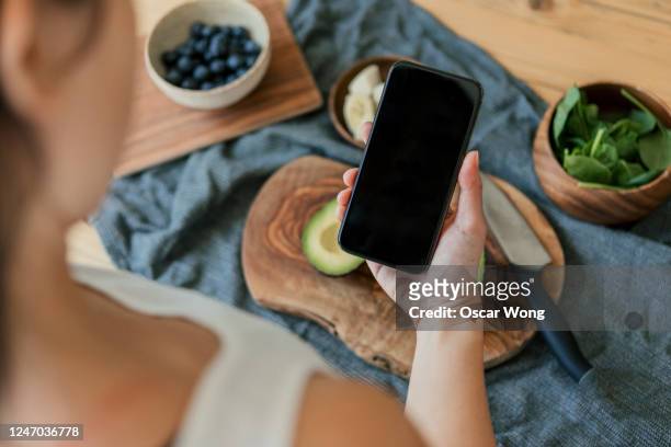 using smartphone while preparing vegan food on a wooden worktop - hands cooking stock pictures, royalty-free photos & images