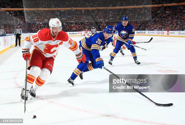Elias Lindholm of the Calgary Flames controls the puck against Rasmus Dahlin of the Buffalo Sabres during an NHL game on February 11, 2023 at KeyBank...