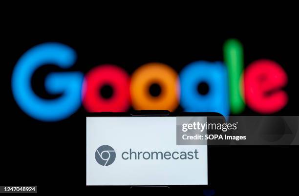 In this photo illustration, the logo of chromecast is seen displayed on a mobile phone screen with a google logo in the background.